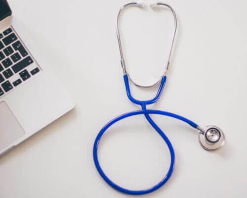 Picture of a stethoscope on a white desk next to a laptop