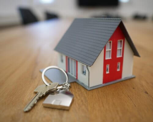 Picture of a small toy house next to a set of house keys