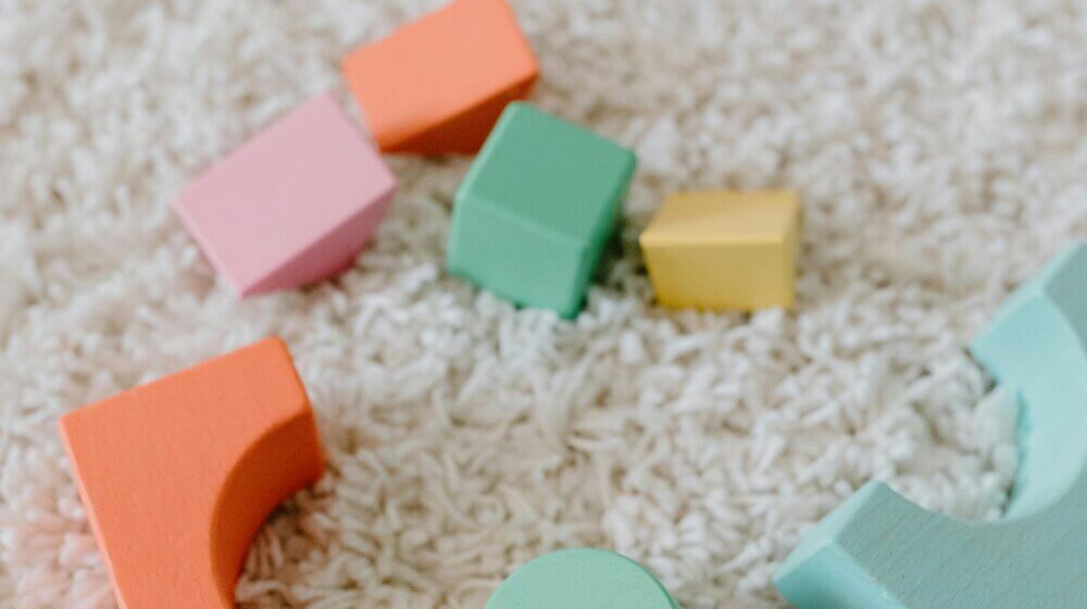 Picture of colourful baby toys sprawled out on a cream carpet